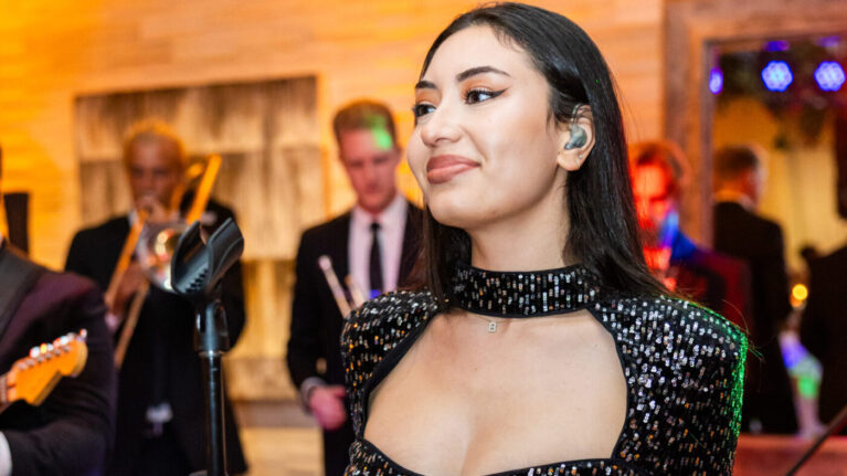 A talented singer performing on stage with a live wedding band, featuring a 20-piece ensemble, creates an electrifying atmosphere at a wedding event. This image showcases the energy and excitement that Ben Mallare Events & Entertainment provides, highlighting the perfect blend of music and celebration for unforgettable wedding experiences.