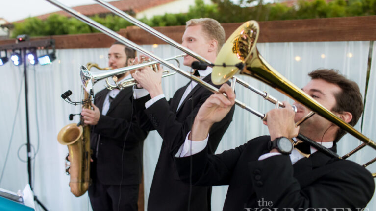 Live wedding band musicians from Ben Mallare Events & Entertainment performing on stage, featuring a saxophonist, trombonist, and trumpeter, enhancing the wedding celebration with vibrant music.