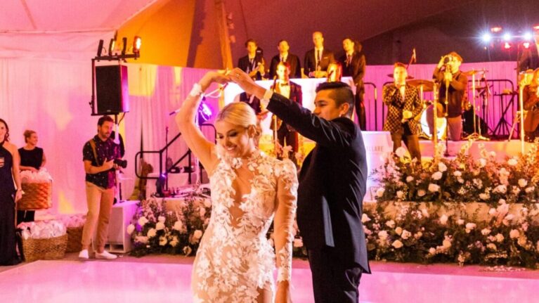 Bride and groom dancing at a wedding reception with a 20-piece live wedding band performing on stage, showcasing Ben Mallare Events & Entertainment's musicians in the background.