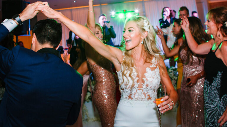 A bride dancing joyfully at a wedding reception with a live 20-piece wedding band performing in the background, showcasing the vibrant atmosphere created by Ben Mallare Events & Entertainment.