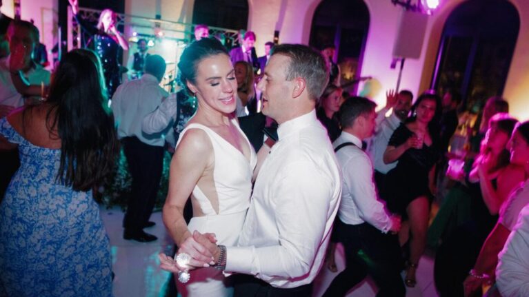A lively wedding reception scene at Ritz-Carlton Bacara featuring a 20-piece wedding band performing on stage while guests dance joyfully. The image captures a couple dancing closely, surrounded by friends enjoying the vibrant atmosphere created by the live music. Ben Mallare Events & Entertainment specializes in providing exceptional live wedding bands that elevate celebrations with unforgettable performances.