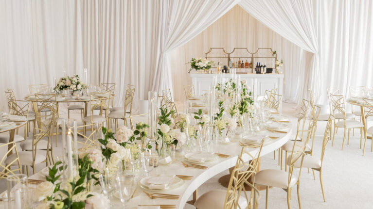 Elegant wedding reception setup with Ben Mallare Entertainment at the Resort at Pelican Hill featuring beautifully arranged tables adorned with floral centerpieces and candles, perfect for a memorable celebration. This sophisticated ambiance is ideal for live wedding bands like those provided by Ben Mallare Events & Entertainment, creating an unforgettable atmosphere for guests to enjoy music and dancing. The tastefully draped ceiling and luxurious decor enhance the experience of live music performances, making it a perfect venue for your special day.