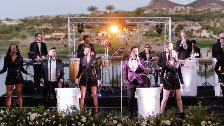 A 20-piece live wedding band from Ben Mallare Events & Entertainment performing on an outdoor stage, featuring multiple musicians and singers, with scenic background and professional lighting.