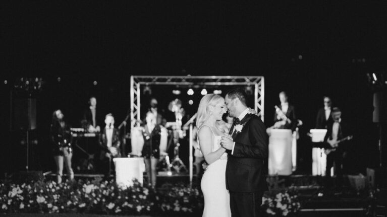 A bride and groom share their first dance in front of a live 20-piece wedding band from Ben Mallare Events & Entertainment, featuring musicians and singers on stage, creating an unforgettable wedding reception atmosphere.
