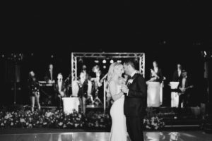 A bride and groom share their first dance in front of a live 20-piece wedding band from Ben Mallare Events & Entertainment, featuring musicians and singers on stage, creating an unforgettable wedding reception atmosphere.