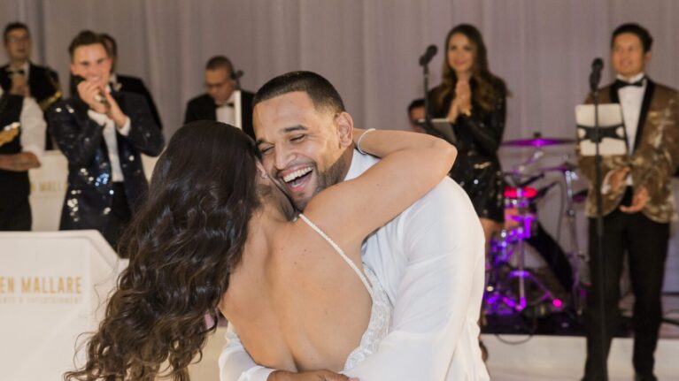 A joyful couple shares a dance during their wedding reception at Pelican Hill, surrounded by a vibrant 20-piece live wedding band from Ben Mallare Events & Entertainment. The musicians, dressed in elegant attire, create an unforgettable atmosphere with their lively performance, enhancing the couple's special moment. This image captures the essence of a memorable wedding celebration, highlighting the importance of live music in creating a magical experience.