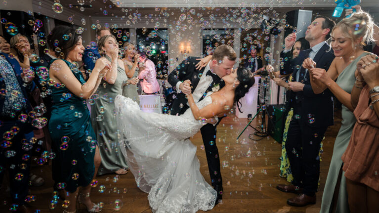 A bride and groom share a romantic dance surrounded by guests and bubbles, with a 20-piece wedding band from Ben Mallare Events & Entertainment performing live music in the background, creating an enchanting atmosphere for the celebration.