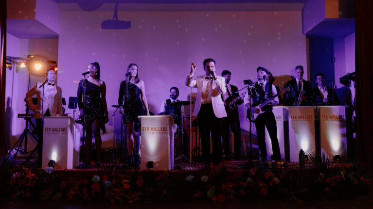 A 20-piece wedding band from Ben Mallare Events & Entertainment performing live on stage with vocalists and instrumentalists, creating an energetic atmosphere for a wedding celebration.