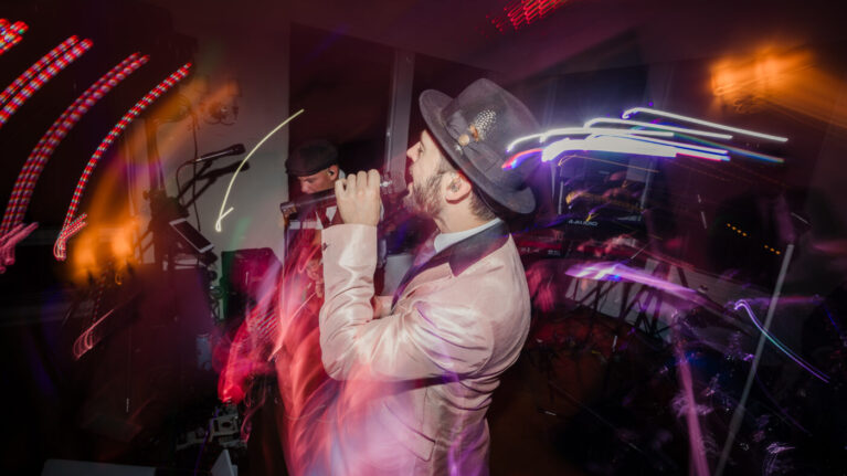 A dynamic live wedding band performer from Ben Mallare Events & Entertainment passionately singing on stage, creating an unforgettable wedding reception experience.