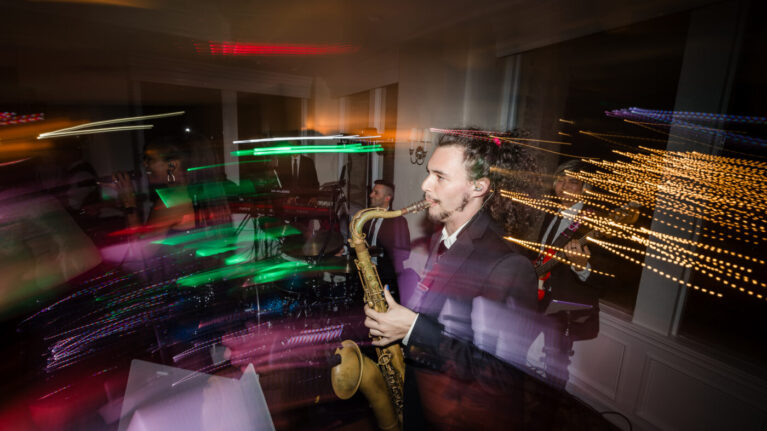 A saxophonist performing with a live wedding band at a Ben Mallare Events & Entertainment event, showcasing vibrant lighting and an energetic atmosphere.