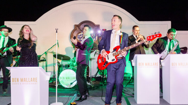 Live wedding band from Ben Mallare Events & Entertainment performing on stage, featuring a 20-piece ensemble with musicians playing guitar, trumpet, and drums, providing high-energy entertainment for wedding receptions.