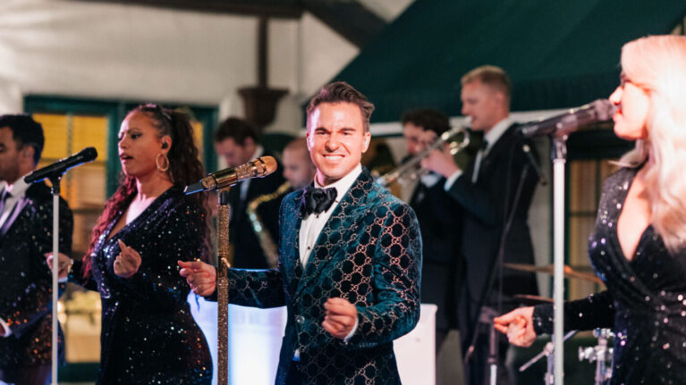 A vibrant 20-piece wedding band from Ben Mallare Events & Entertainment performing live, featuring singers and musicians on stage, creating an energetic atmosphere for a wedding celebration. A vibrant 20-piece wedding band from Ben Mallare Events & Entertainment performing live, featuring singers and musicians on stage, creating an energetic atmosphere for a wedding celebration.