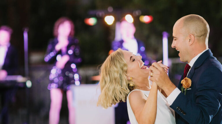 A joyful couple dances at their wedding reception with a live wedding band performing in the background, featuring musicians from Ben Mallare Events & Entertainment.