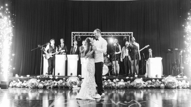 A bride and groom share a dance in front of a 20-piece live wedding band from Ben Mallare Events & Entertainment, featuring musicians and singers on stage, creating a memorable wedding reception atmosphere.