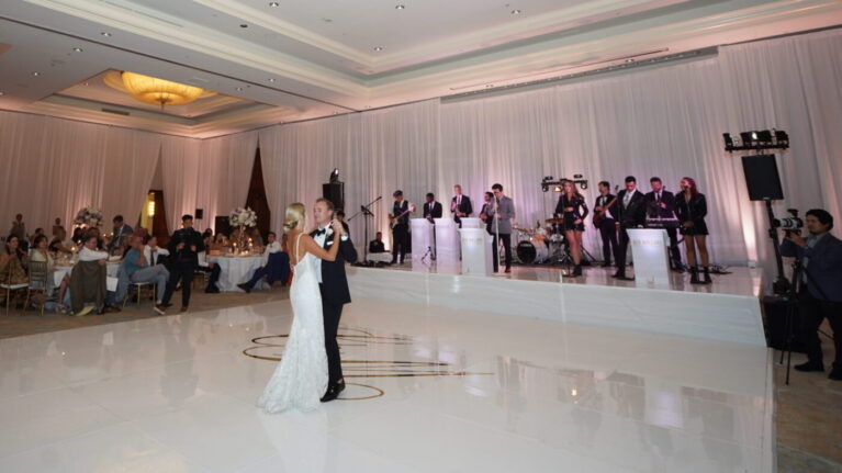 A bride and groom share their first dance in front of a 20-piece live wedding band from Ben Mallare Events & Entertainment, with musicians and singers performing on stage, creating an elegant and lively atmosphere for the wedding reception.