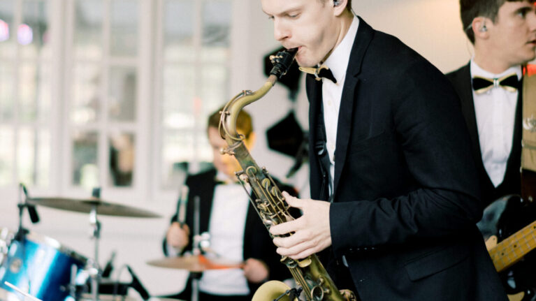 Live wedding band musicians performing on stage, featuring a saxophonist and other instrumentalists, showcasing Ben Mallare Events & Entertainment's 20-piece wedding band.