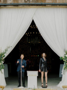 Two musicians from a 20-piece wedding band performing on stage at a wedding event organized by Ben Mallare Events & Entertainment, with elegant white drapery and floral arrangements in the background.
