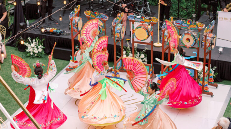 A vibrant 20-piece wedding band from Ben Mallare Events & Entertainment performing live at an outdoor wedding, with dancers in colorful attire enhancing the lively atmosphere. A vibrant 20-piece wedding band from Ben Mallare Events & Entertainment performing live at an outdoor wedding, with dancers in colorful attire enhancing the lively atmosphere.