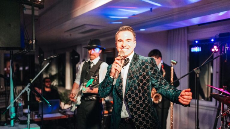 A 20-piece wedding band from Ben Mallare Events & Entertainment performing live, featuring a lead singer and musicians playing guitar and saxophone, creating an unforgettable wedding reception experience.