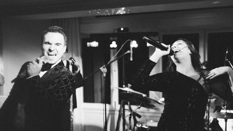 A dynamic live wedding band from Ben Mallare Events & Entertainment performing on stage, featuring male and female vocalists passionately singing.