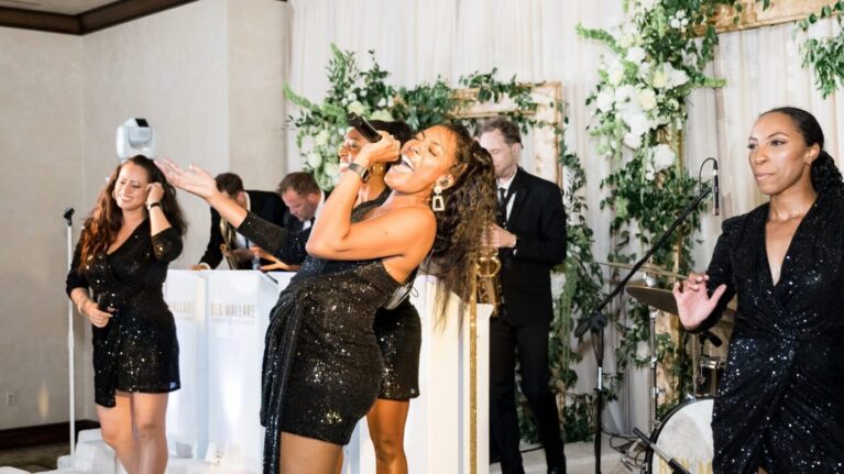 A vibrant live wedding band performance featuring a talented female singer captivating the audience with her energetic vocals. The 20-piece wedding band, part of Ben Mallare Events & Entertainment, creates an unforgettable atmosphere, enhancing the celebration with live music and entertainment. This image showcases the joy and excitement that a professional wedding band brings to special events, making it a perfect choice for couples looking to elevate their wedding experience.