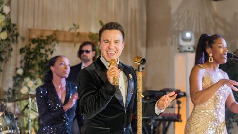 A lively performance by a talented 20-piece wedding band, showcasing dynamic singers at a wedding event. The lead vocalist, dressed elegantly, captivates the audience with a golden microphone, while fellow musicians enhance the festive atmosphere. This image highlights the vibrant energy and professional entertainment provided by Ben Mallare Events & Entertainment, perfect for couples seeking live wedding bands to create unforgettable memories on their special day.