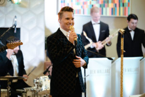 A 20-piece wedding band from Ben Mallare Events & Entertainment performing live, featuring a lead singer and musicians playing instruments on stage.